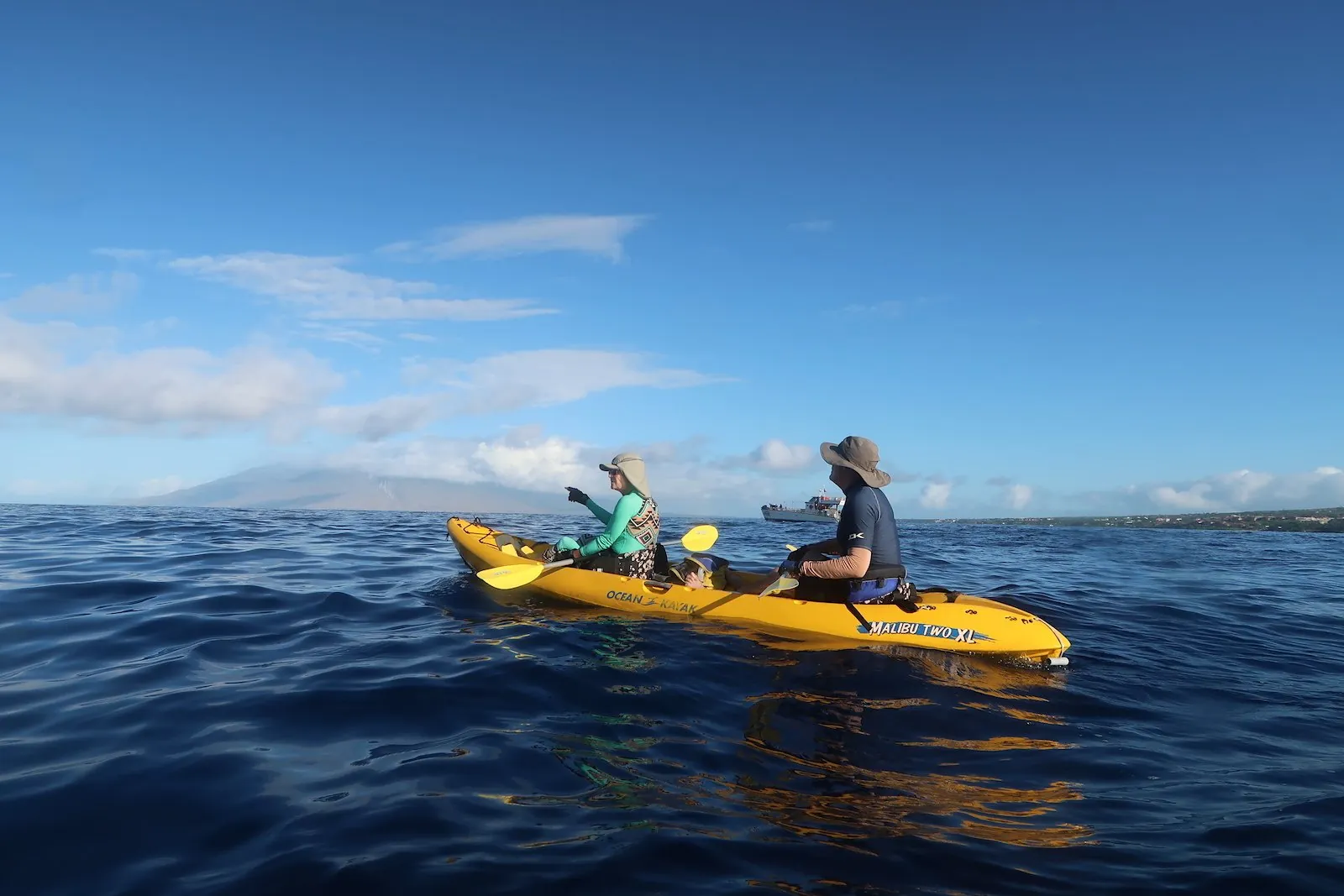 Guide and guest in a yellow tandem kayak pointing across open blue water