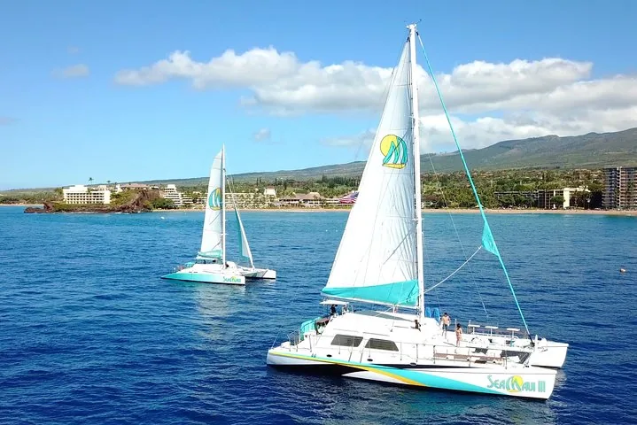 Two Sea Maui sailing catamarans offshore with beachfront hotels and green mountains behind