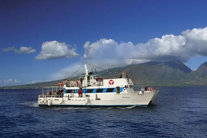 The white multi-deck Kaulana under way with green mountains and clouds behind