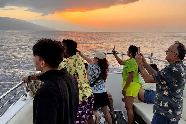 Guests at the bow photographing an orange sky low over the ocean