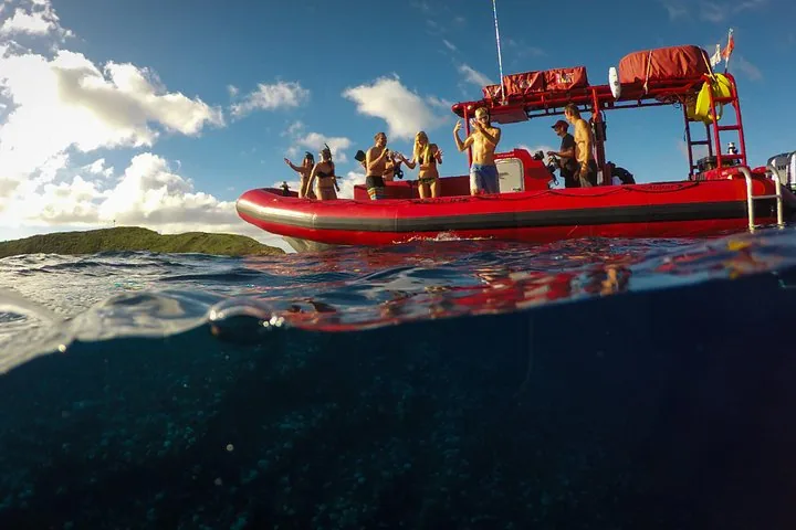 Half-underwater view of guests standing on a red raft under a bright sky